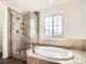 Luxurious bathroom features a glass-enclosed shower, a soaking tub, and stylish tile work at 5843 S Danube St, Aurora, CO 80015