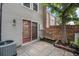 Private patio with brick wall, small lawn area, and access from a red door at 1150 Inca St # 59, Denver, CO 80204