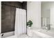 Bathroom featuring a modern white sink and toilet, contrasting with dark gray tile in the shower area at 1206 S Reed St, Lakewood, CO 80232