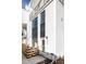 Modern townhome featuring white siding, black accents, a small fence, and a well-lit entrance at 1206 S Reed St, Lakewood, CO 80232