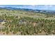 An aerial view of a luxurious mountain home surrounded by tall pine trees and rolling hills with beautiful mountain views at 24701 Us Hwy 40, Golden, CO 80401
