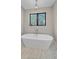 Bathroom featuring soaking tub, marble tile, and view to outside at 24701 Us Hwy 40, Golden, CO 80401