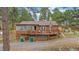 Log cabin featuring an expansive deck, stone chimney, and additional covered outdoor space at 24701 Us Hwy 40, Golden, CO 80401