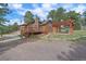 Exterior view of a log cabin with a covered patio, stone chimney, and surrounding trees at 24701 Us Hwy 40, Golden, CO 80401