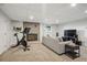 Carpeted living room includes a grey sofa, brick fireplace, exercise bike and a mounted television at 6755 Garrison St, Arvada, CO 80004