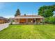 Expansive backyard featuring a well-manicured lawn, a brick patio, and mature trees at 2121 W 73Rd Pl, Denver, CO 80221