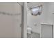 Bathroom showcasing a clear glass shower door, toilet, small window and a white storage cabinet at 2121 W 73Rd Pl, Denver, CO 80221