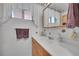 Bathroom with white sink vanity, decorative wallpaper border and a framed mirror at 2121 W 73Rd Pl, Denver, CO 80221