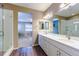 Ensuite bathroom featuring double vanity, framed mirrors, and glass shower with dark plank flooring at 22662 E Narrowleaf Cir, Aurora, CO 80016