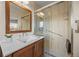 Modern bathroom with wood cabinets, a large mirror, and a walk-in shower at 8205 Pennsylvania St, Denver, CO 80229