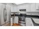 Modern kitchen featuring stainless steel appliances, light wood floors, black counters and white cabinetry at 701 Harlan St # E29, Lakewood, CO 80214