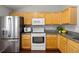 Well-lit kitchen featuring light wood cabinets, stainless steel refrigerator, and granite countertops at 13906 Jackson St, Thornton, CO 80602
