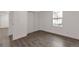 A bedroom with modern gray wood-style flooring, a window with security bars, and a sliding closet door at 1326 Sable Blvd, Aurora, CO 80011