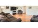 Spacious living room with hardwood floors, a plush brown couch, and a large television at 9882 Harris St, Thornton, CO 80229