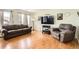 Inviting living room features beautiful hardwood floors, a brown couch, and a comfortable armchair at 9882 Harris St, Thornton, CO 80229