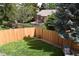 Landscaped backyard with a wooden fence, lush green lawn, and mature trees, offering a private outdoor space at 12498 W Prentice Dr, Littleton, CO 80127