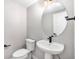 Bright powder room featuring a round mirror, white fixtures, and modern black hardware at 2078 S Holly St # 1, Denver, CO 80222