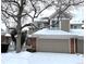 Two-story townhome with attached garage, snow-covered landscaping, and brick accents at 9866 Carmel Ct, Lone Tree, CO 80124