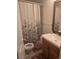 Clean bathroom with a shower/tub combo, wood vanity, and floral shower curtain at 19877 E 40Th Ave, Denver, CO 80249