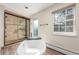 Bright bathroom featuring soaking tub, glass shower, and large window at 3577 S Hillcrest Dr, Denver, CO 80237