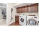 Well-equipped laundry room featuring modern washer and dryer, storage cabinets, and wood flooring at 3577 S Hillcrest Dr, Denver, CO 80237