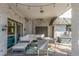 Covered patio with brick wall, white cushioned outdoor seating, and stylish decor and lighting at 3577 S Hillcrest Dr, Denver, CO 80237