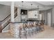 Finished basement bar area with stone accents, bar seating, a fridge, and a TV for entertaining at 10531 Lieter Pl, Lone Tree, CO 80124