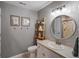 Neutral bathroom with a ladder shelf, decorative wall art, and vanity with a round mirror at 10531 Lieter Pl, Lone Tree, CO 80124
