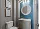 Charming half-bath with blue accent wall, framed art, round mirror, and modern vanity at 10531 Lieter Pl, Lone Tree, CO 80124