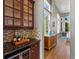 Hallway with beverage station, glass cabinets, granite countertop, wood floors, and lots of natural light at 10531 Lieter Pl, Lone Tree, CO 80124