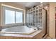 Bright jetted tub with tile surround, glass block and a window that provides natural light at 5604 S Lisbon Way, Centennial, CO 80015