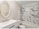 Updated bathroom features marble-look tile surround, modern vanity, and oval mirror at 3460 S Poplar St # 404, Denver, CO 80224