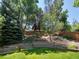 Well-manicured backyard with mature trees, terraced landscaping, and a privacy fence at 2548 Foothills Canyon Ct, Highlands Ranch, CO 80129