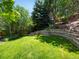 Lush backyard featuring a tiered retaining wall, vibrant grass, and privacy provided by mature trees at 2548 Foothills Canyon Ct, Highlands Ranch, CO 80129