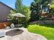 Lovely backyard features stone patio with umbrella table and chairs, beautiful landscaping, and lush green grass at 2548 Foothills Canyon Ct, Highlands Ranch, CO 80129