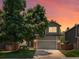 Charming home with a well-maintained lawn, mature trees, and a two-car garage against a beautiful sunset sky at 2548 Foothills Canyon Ct, Highlands Ranch, CO 80129