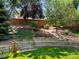 Multi-tiered landscaping in the backyard, featuring lush greenery, stone retaining walls, and manicured lawn at 2548 Foothills Canyon Ct, Highlands Ranch, CO 80129