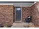 Close-up of front entryway and door with brick facade and small chair at 1581 S Kendall St, Lakewood, CO 80232
