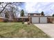 Charming brick home featuring an attached two-car garage and well-manicured lawn and landscaping at 1581 S Kendall St, Lakewood, CO 80232