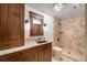Beautiful bathroom featuring a stone tiled shower, granite counters, and wood cabinets at 8225 Fairmount Dr # 10-203, Denver, CO 80247