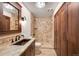 Modern bathroom featuring a stone tiled shower, granite counters, wood cabinets, and great lighting at 8225 Fairmount Dr # 10-203, Denver, CO 80247