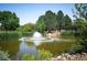Exterior view of a serene pond with a fountain surrounded by trees and landscaping at 8225 Fairmount Dr # 10-203, Denver, CO 80247