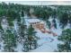 Expansive aerial view of a snow-covered home, nestled among mature evergreens, with a deck and pool at 757 N Bluff Dr, Franktown, CO 80116