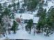 Aerial view of snow-covered exterior and roof of the house showcasing the surrounding pine tree landscape at 757 N Bluff Dr, Franktown, CO 80116