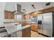 Well-lit kitchen with stainless steel appliances, wooden cabinets, and modern vent hood at 12455 W Alameda Dr, Lakewood, CO 80228