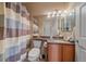 Bathroom features a sink, toilet, neutral colors, tile floor, and a shower with blue and gray curtains at 22124 E Euclid Dr, Aurora, CO 80016