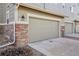 Attached one-car garage featuring stone accents, a classic coach light, and a neutral-colored door at 1601 Venice Ln, Longmont, CO 80503