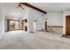 Open-concept living room with beam, neutral carpet, staircase railing, and views of the breakfast nook and kitchen at 11203 W Dorado Ave, Littleton, CO 80127