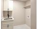 A laundry room with a sink, white cabinets, dark hardware, and a shelf at 5550 Wetlands Dr, Longmont, CO 80504