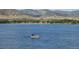 Calm lake scene with a pontoon boat afloat on the serene blue waters surrounded by distant hills at 9694 Meeker St, Littleton, CO 80125